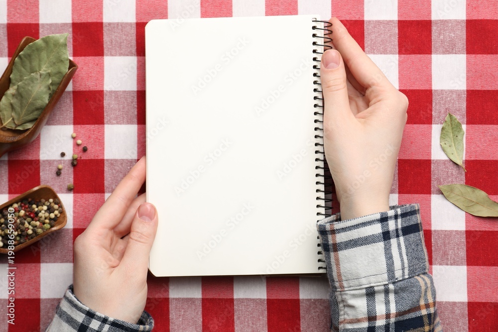 Obraz premium Woman with recipe book and different spices at table, top view