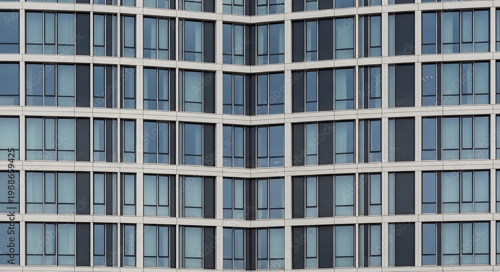 Obraz premium Modern Glass Building Facade with Repeating Window Patterns.