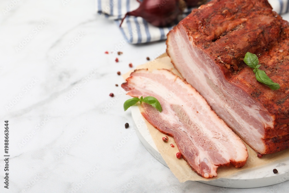 Fototapeta premium Pieces of smoked bacon and spices on white marble table, closeup. Space for text