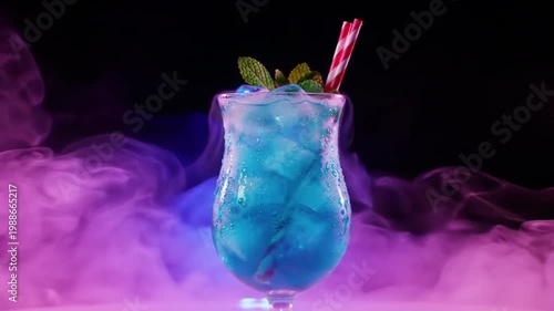 Blue tropical cocktail with mint and straws in purple smoke