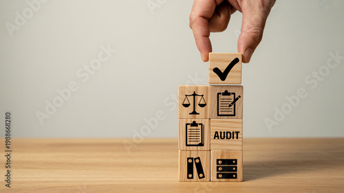 A hand placing a checkmark block on top of a stack of audit blocks