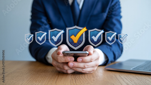 A businessman sitting at a desk with a smartphone and laptop, surrounded by security checkmarks and shields.