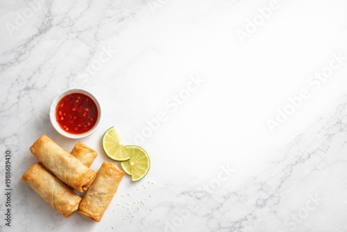 Spring rolls with sauce and lime on marble background with copy space