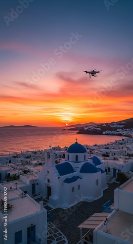 Aerial view of whitewashed village with blue domes at sunset, drone overhead