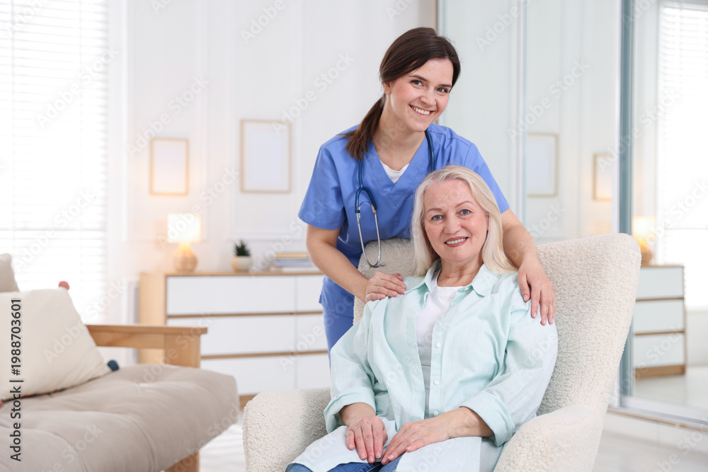 Fototapeta premium Portrait of smiling care worker with senior woman at nursing home. Space for text