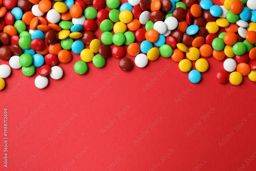 Obraz premium Delicious colorful candies on red background, top view. Space for text