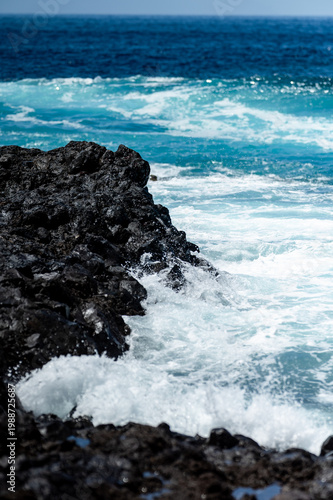 Turquoise ocean waves crashing on volcanic rocks coastline in Tenerife Canary Islands Spain, powerful Atlantic sea, blue water motion, dramatic seascape, summer travel destination, natural energy