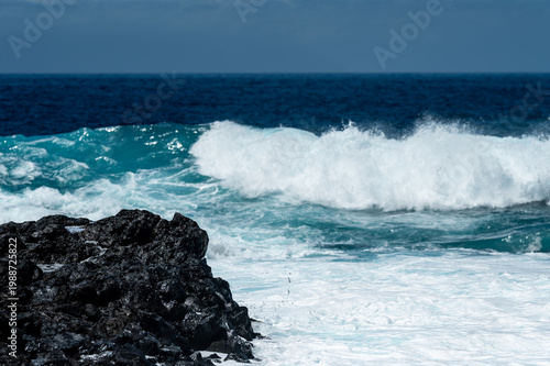 Turquoise ocean waves crashing on volcanic rocks coastline in Tenerife Canary Islands Spain, powerful Atlantic sea, blue water motion, dramatic seascape, summer travel destination, natural energy
