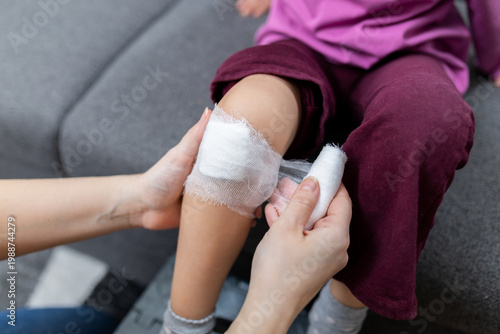Photography Parent wrapping bandage on child knee after minor injury at home