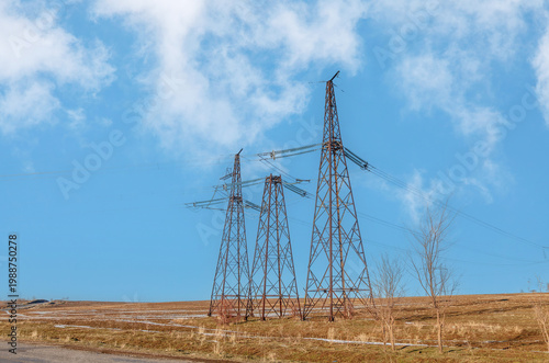 Fotografía three metal poles of high-voltage power lines in a field against the sky