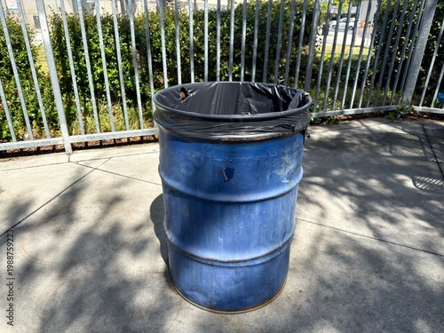 Fotografía Industrial Outdoor Waste Bin: A large blue barrel-style trash can with a black liner, designed for high-traffic public facilities and industrial waste management