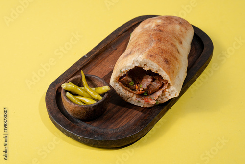 Doner kebab on wooden tray isolated on yellow background