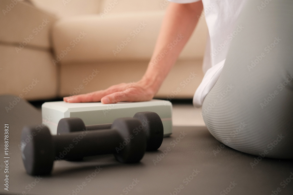 Fototapeta premium Woman ready to sport exercises at home. Sport workout on yoga mat with yoga block, dumbbells