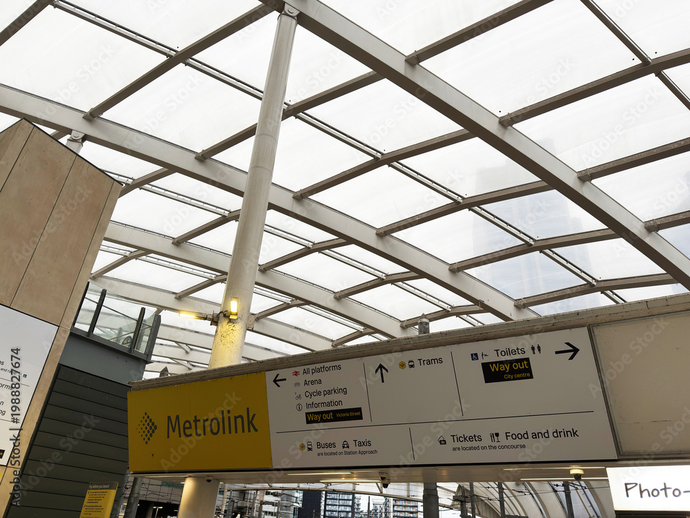 Fototapeta premium Metrolink station interior with modern glass canopy and directional signage at Manchester UK tram stop showing platforms tickets toilets and way out