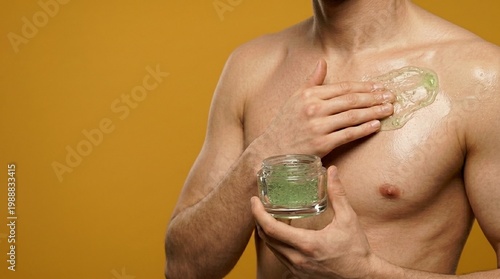 Man applying moisturizing gel on chest. Skin care routine of man with beauty cosmetic product. Hydration treatment, body cream hygiene and dermatology procedure for male health, yellow background.