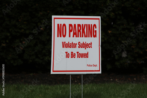 A city street lined with trees, a clear sidewalk, a row of NO PARKING signs and pedestrian 