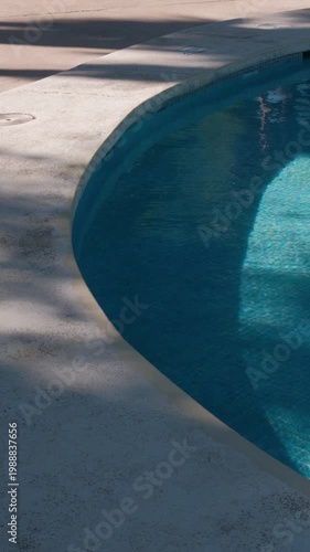 PORTOCOLOM, MALLORCA, SPAIN - OCTOBER, 2025: Bright midday sun shines on a refreshing swimming pool at a Portocolom resort, creating strong long shadows