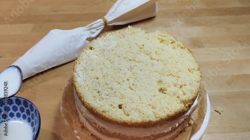 Cake rotating on a stand while a baker spreads cream frosting. Close-up of decorating process, smooth icing, professional or home pastry work, dessert preparation, bakery concept, sweet food video