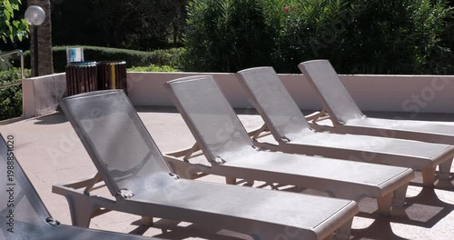 PORTOCOLOM, MALLORCA, SPAIN - OCTOBER, 2025: Bright midday sun shines on empty sun loungers and umbrellas in Portocolom, creating strong contrast and shadows.