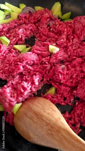 First person view of frying minced beef with onion and avocado in pan during cooking process meal preparation