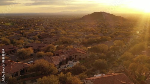 A 4k aerial view of a desert landscaped home in Arizona featuring a travertine tiled pool deck, fireplace and out door kitchen.