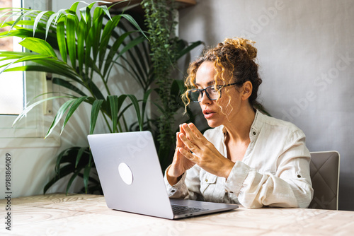Konstfotografi Woman concentrating on laptop during remote meeting in bright home office with h