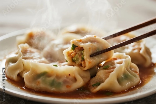 Steaming dumplings with vegetable filling served on a plate, being lifted with chopsticks