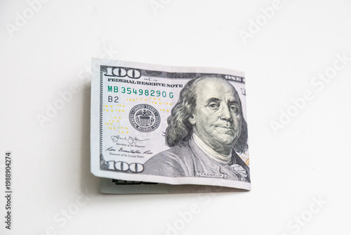 A single one hundred dollar bill folded in half on a clean white background, showcasing the portrait of Benjamin Franklin and the official markings of the United States Federal Reserve currency