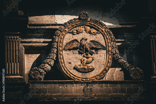 Mexican national emblem eagle on cactus carved in historic stone facade