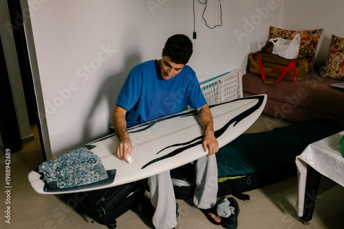 Surfer waxing his board getting ready to go on a surfing practice