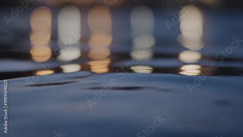 Abstract bokeh reflection of city lights on dark rippling water