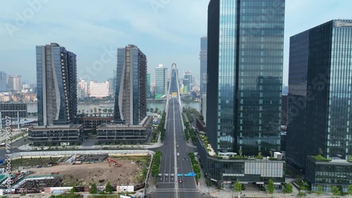 Urban boulevard framed by modern high-rise buildings leading toward iconic bridge, showcasing planned city infrastructure in Ho Chi Minh City.