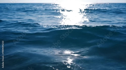 Sunlight reflects on rippling ocean waves in a serene natural scene.