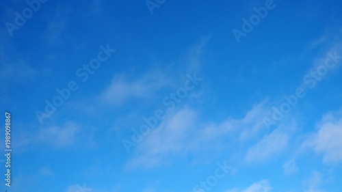 The sky shows a deep blue color with white clouds. Clouds drift quietly and change shape over time. This takes place in the afternoon with clear skies above.