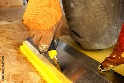 Worker cutting blue polystyrene foam heat insulation with old retractable utility knife, closeup detail