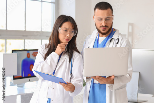 Doctors analyzing scientific data on laptop in laboratory