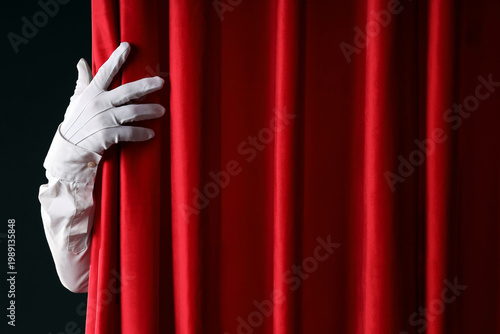 Bild auf Leinwand Magician's hand behind red curtains on dark background