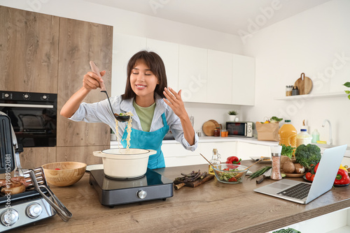 Young woman making soup in ...