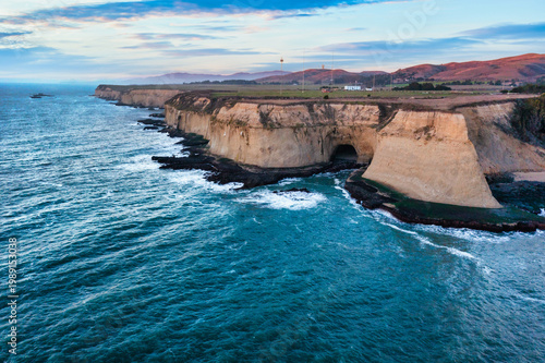Sunset over rock arch at Martins Beach near Half Moon Bay California with Pacific Ocean waves and warm golden light along the rugged coastline