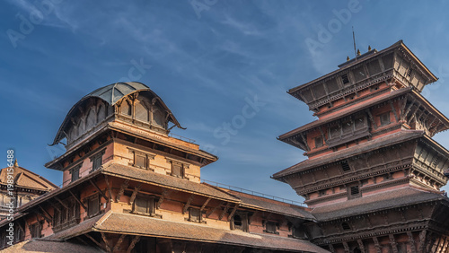 The famous Newar architecture. Multi-tiered roofs of ancient pagodas against a background of blue sky and clouds. Beautiful wood carvings, barred windows and balconies. Nepal. Kathmandu. Durbar Square