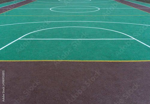 Colorful sports court background. Top view to green and brown field rubber ground with white lines outdoors. High angle of part large yard with modern sports ground for playing football, basketball. 