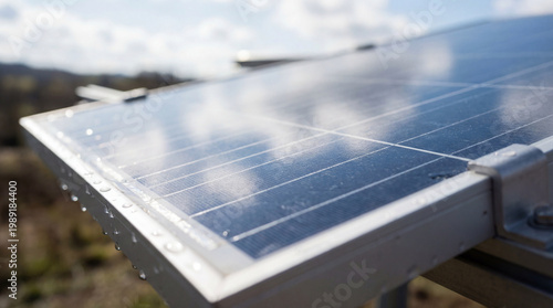 Closeup of a solar panel with water droplets on the frame under a cloudy sky