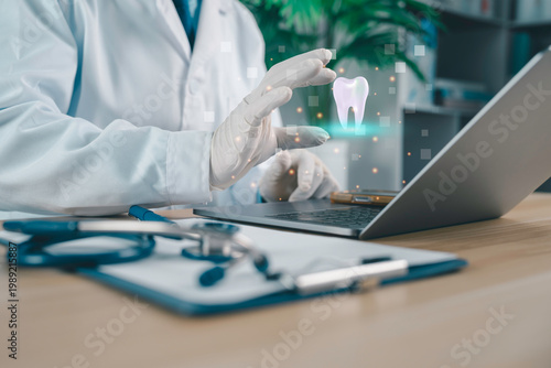 Dentist using laptop with digital tooth hologram, modern dental technology, oral healthcare innovation