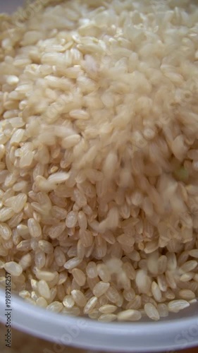 Brown rice pouring into funnel, food processing and grain production concept, vertical, video