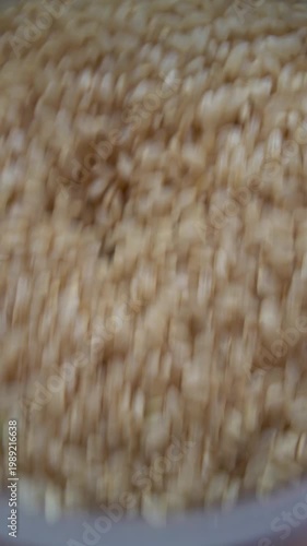 Brown rice pouring into funnel, food processing and grain production concept, vertical, video