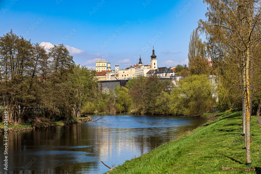 Obraz premium Picturesque river flows through a green landscape towards a historic European town
