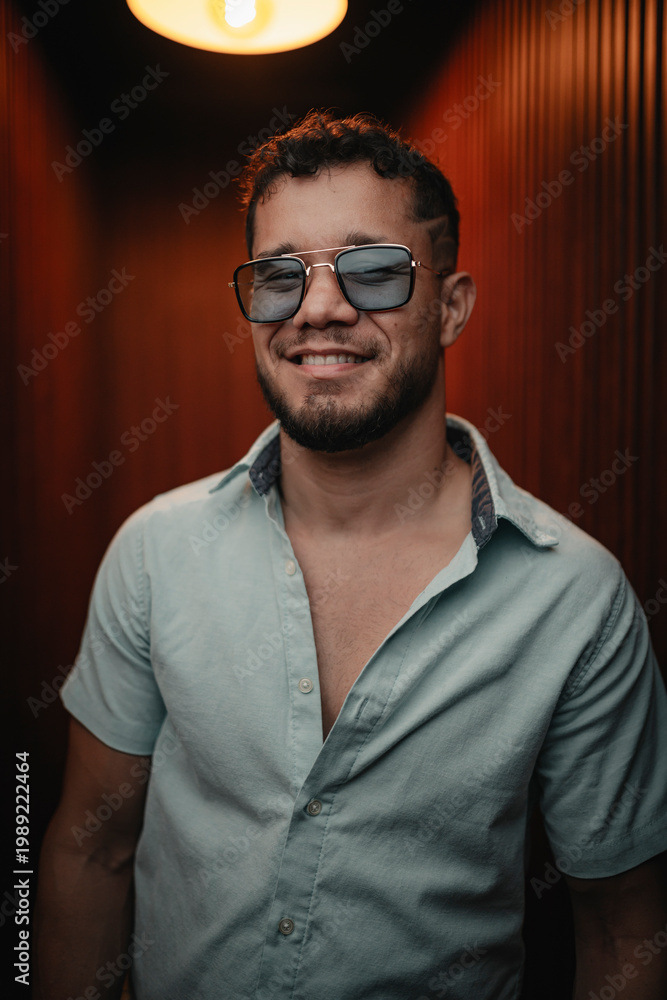 Fototapeta premium Smiling young man wearing sunglasses expressing happiness