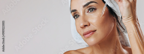 Photos Skincare, thinking or mature woman with dropper in studio, apply hyaluronic acid or anti aging treatment