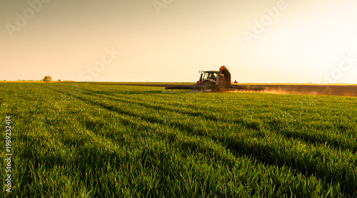 Farmer in tractor spraying crops at sunset