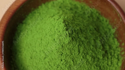 Matcha green tea powder in a wooden cup.